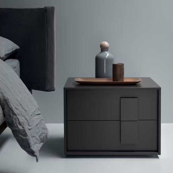 Dark grey bedside table with modern graphic handles in a minimalist bedroom